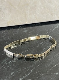 a gold and silver bracelet on a marble table