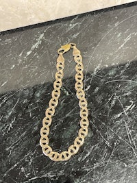 a gold chain bracelet on a marble table