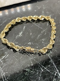 a gold chain bracelet on a marble table