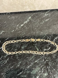 a gold chain necklace on a marble counter