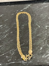 a gold chain bracelet on a marble table