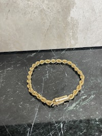 a gold chain bracelet on a marble countertop