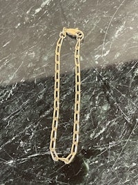 a gold chain bracelet on a marble surface